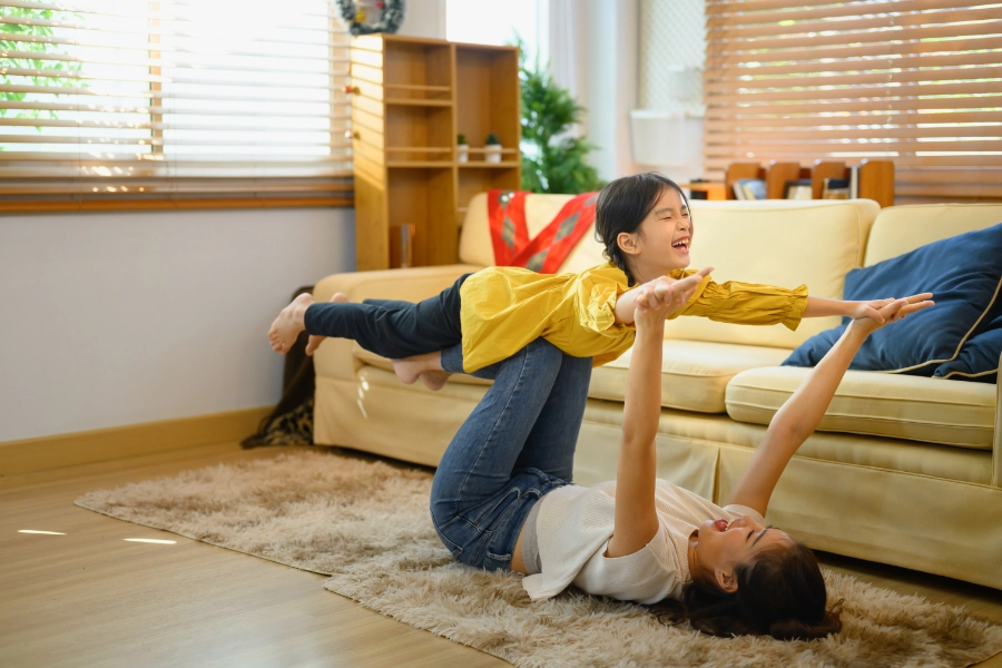 Tochter und Mutter spielen Flugzeug in Wohnzimmer
